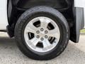 A close-up of a silver wheel with five spokes and a black tire labeled Destination A/T on a Chevrolet Silverado 1500