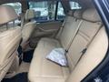 Interior view of the backseat of a 2009 BMW X5 featuring tan leather seats and a gray item on the seat