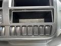 Dashboard controls of a 2018 Hino 195 with a series of black buttons and an empty storage compartment above