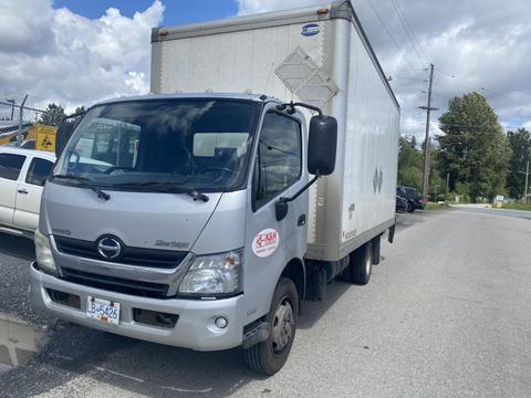 2012 Hino XJC720 box truck in gray with a cab and a large cargo area on the back displaying company branding on the side