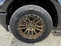 A close-up of a bronze alloy wheel on a black 2019 RAM 1500 featuring rugged tires and detailed patterns on the rim