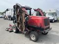 A red 2012 Toro Groundsmaster 5910 with several mower decks attached tilting to one side and an open cabin revealing the interior controls
