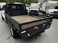 A black 2020 Ford F-350 SD truck with a flatbed featuring a wood surface and metal sides designed for carrying cargo