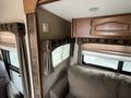 Interior view of a 2013 Outdoor Wind River showing a sofa and window treatments with light-colored curtains and wooden cabinetry above