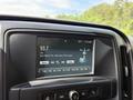 A close-up view of the touchscreen infotainment system in a 2016 Chevrolet Silverado 2500HD displaying radio station information and song details