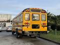 A yellow 2013 International 4300 school bus viewed from the rear with multiple lights and a distinctive boxy shape