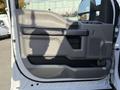 A 2019 Ford F-550 door panel featuring a gray design with a black armrest and handle a textured surface and a small storage compartment