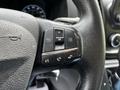 Close-up of a steering wheel control panel in a 2022 Ford Transit featuring buttons for voice control navigation and phone functions