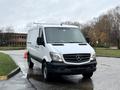 A 2017 Mercedes-Benz Sprinter van in white with a black grille and headlights parked on a wet road