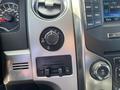 Close-up of the control panel in a 2014 Ford F-150 showing the trailer brake control dial and adjacent buttons for four-wheel drive settings and audio controls