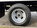 A close-up of a rugged tire mounted on a 2015 GMC Savana with a silver aluminum wheel featuring five bolt holes and the GMC logo in the center