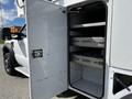 A 2008 Ford F-550 with an open storage compartment featuring several metal shelves and drawers inside the compartment