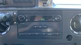 Dashboard of a 2013 Ford Econoline featuring a radio display with knobs and buttons for audio control