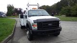 A 2008 Ford F-450 SD with a white body and black grille featuring a utility bed and ladder rack on top