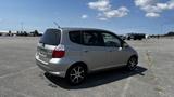 A silver 2006 Honda Fit parked in an open area showcasing its compact design and hatchback style