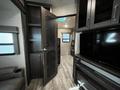 Interior view of a 2021 Grand Design Recreational 311BHS showing an open door to a living area with a television and cabinetry