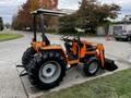 A 2001 Agco ST40 tractor with large black tires an orange body and a front loader attachment parked on a concrete surface