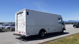 A white 2006 Ford Econoline truck with a boxy cargo area and a single rear door parked in an open area