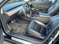 Interior view of a 2019 Tesla Model 3 featuring black leather seats a wooden dashboard and a sleek design with a central touchscreen display