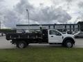 A 2021 Ford F600 with a flatbed and toolboxes on the side, featuring a black and white color scheme and a single cab design