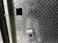 A silver metallic door of a 1995 Freightliner FL70 featuring two locking mechanisms one round and one rectangular embedded in a diamond plate surface