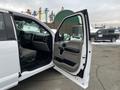 A white 2017 Ford F-150 with an open driver's side door showcasing the interior details and a grey seat