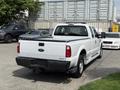 A white 2008 Ford F-250 Super Duty truck with a standard bed and extended cab parked with other vehicles in the background