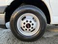A close-up of a silver 2015 GMC Savana wheel featuring a black tire with a visible tread pattern and a six-bolt wheel design