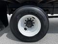 Close-up of a black truck tire with a white rim featuring a six-lug bolt pattern and brand markings on the sidewall