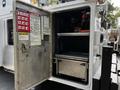 A 2016 Ford F-550 service truck with an open compartment displaying shelves and equipment inside