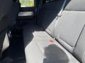 The interior of a 2014 Ford F-150 showing the back seat with black fabric upholstery and seat belts