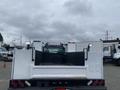 A 2003 Ford F-450 Super Duty truck with an open bed featuring side compartments and lights mounted on the roof