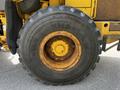 A large yellow wheel from a 2010 John Deere 444K heavy equipment machine showing deep treads and worn surface details