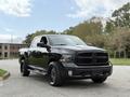 A black 2018 RAM 1500 pickup truck with a bold front grille and large tires parked on a paved surface