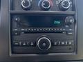 The dashboard control panel of a 2020 Chevrolet Express featuring a radio display with buttons for tuning and volume as well as climate control knobs