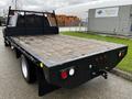 A 2017 Ford F-550 with a flatbed design featuring a wooden surface and a metallic frame with tail lights and a hitch at the rear