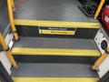 A set of stairs leading up into a vehicle featuring yellow handrails and a sign that reads Welcome aboard Watch your step