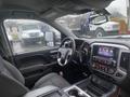 Interior of a 2015 GMC Sierra 1500 featuring a steering wheel dashboard and center console with controls and a touchscreen display