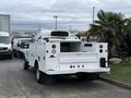 A white 2013 Ford F-350 SD with a tank and maintenance equipment on the bed parked in a lot