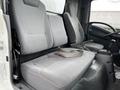 Interior view of a 2022 Isuzu NPR showing two gray cloth seats with seatbelts and an empty space in between for a third seat