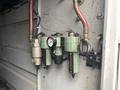 A set of industrial air pressure regulators and filters mounted on a wall with various pipes connected to them