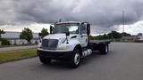 A white 2015 International DuraStar 4300 flatbed truck with a prominent front grille and two side mirrors positioned in a parking lot