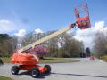 A 2008 JLG Boom Lift with a raised platform and orange and beige coloring showcasing its extendable arm and large wheels designed for lifting heavy objects