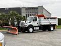 A 2012 International 7400 plow truck with an orange snow plow attached to the front and a white dump bed at the rear