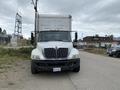 A 2014 International Durastar truck facing the viewer with a white front and a large cargo box in the back