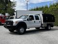 A 2016 Ford F-550 in white with a black utility bed and silver trim featuring side compartments and a front bumper guard