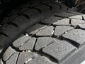 Close-up of a tire tread from a 2012 Autocar Xpert showing deep grooves and rough texture with visible wear and small pebbles embedded in the surface