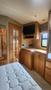Interior of a 2007 Winnebago Adventure featuring a bed with a quilted mattress wooden cabinetry and a small television mounted on the wall