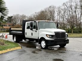 A 2012 International TerraStar truck with a white cab and black bed parked on a wet surface