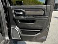 The interior door panel of a 2022 RAM 3500 featuring black leather upholstery polished chrome handle and control buttons